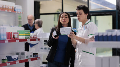 pharmacist customer comparing vitamin boxes reading usage instruction